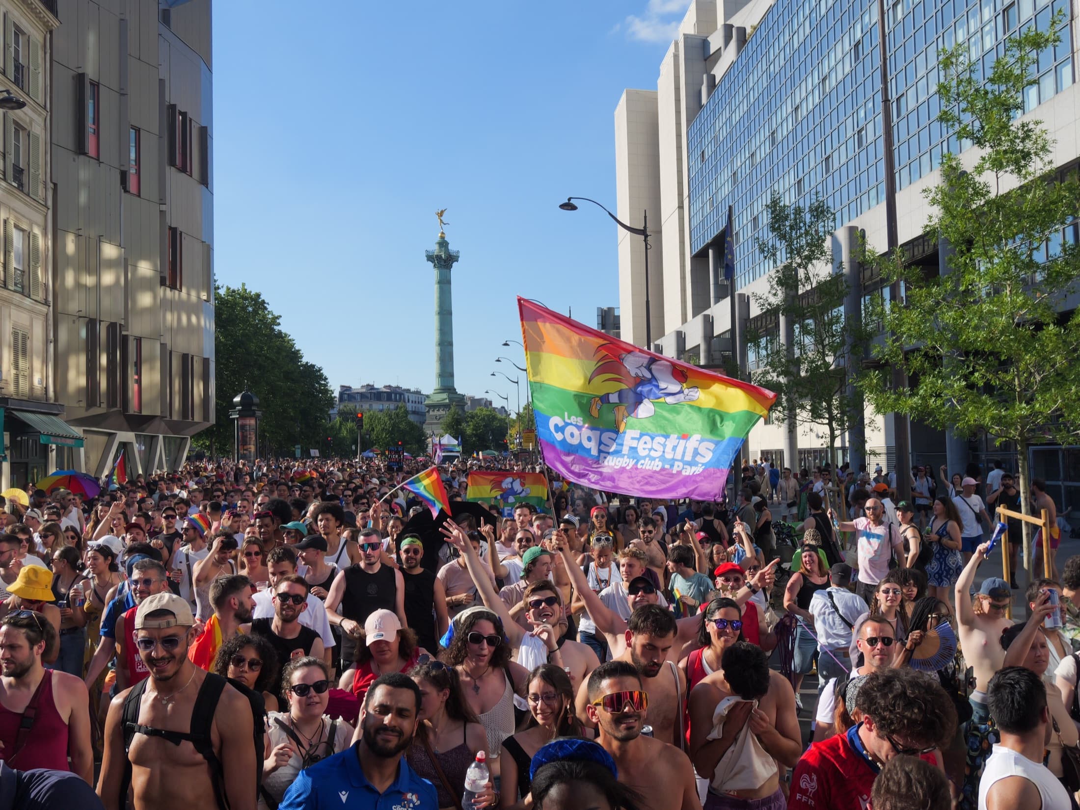La foule de la Marche des Fiertés de Paris derrière le drapeau des Coqs Festifs