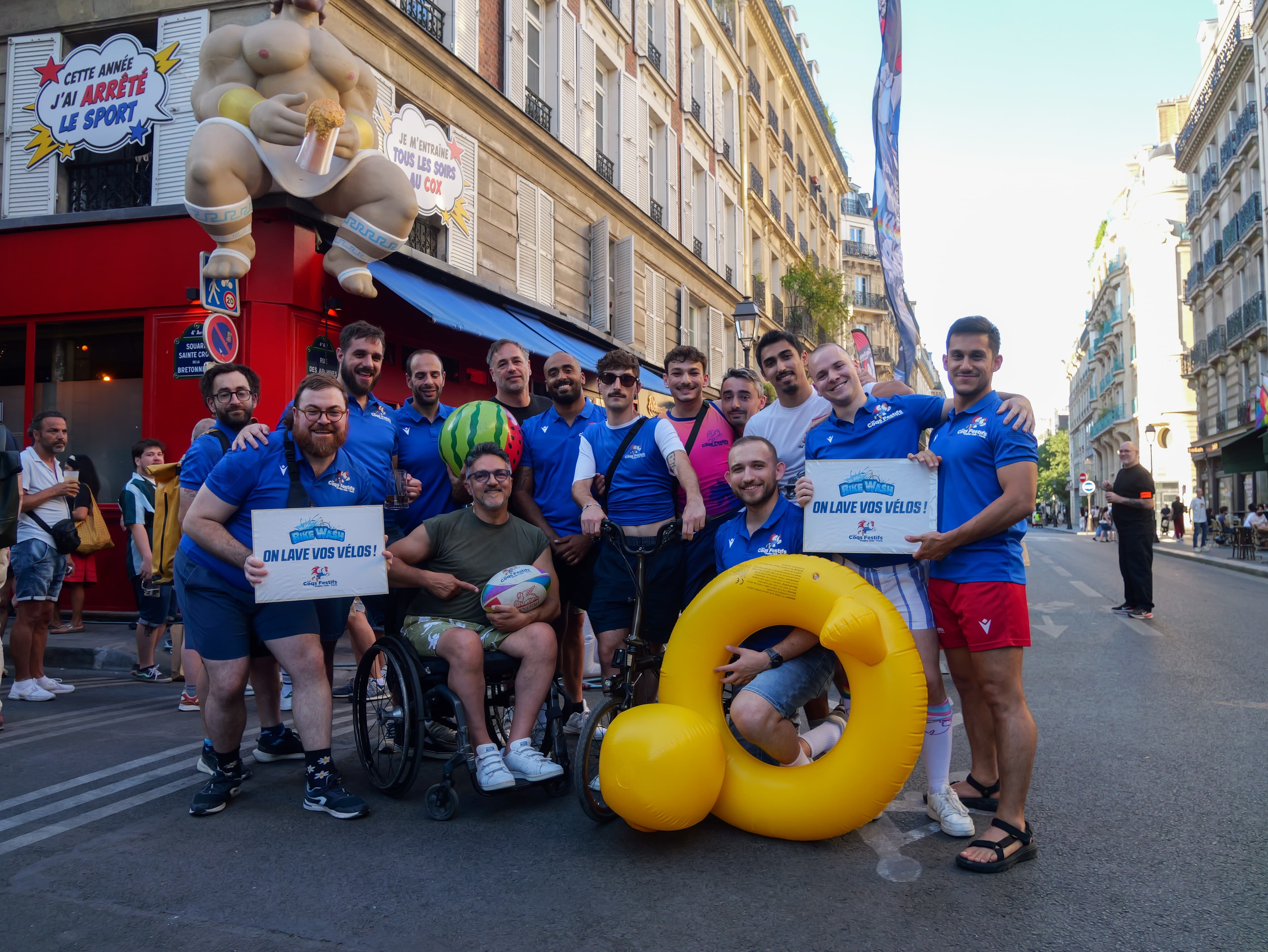 Les Coqs Festifs posant dans la rue avec leur mascotte lors de la Marche des Fiertés